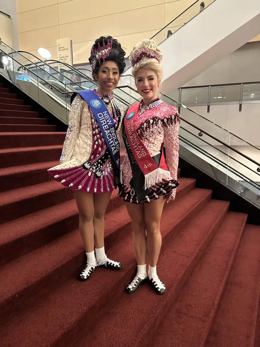 Two championship dancers in embroidered dresses wearing New England Oireachtas sashes